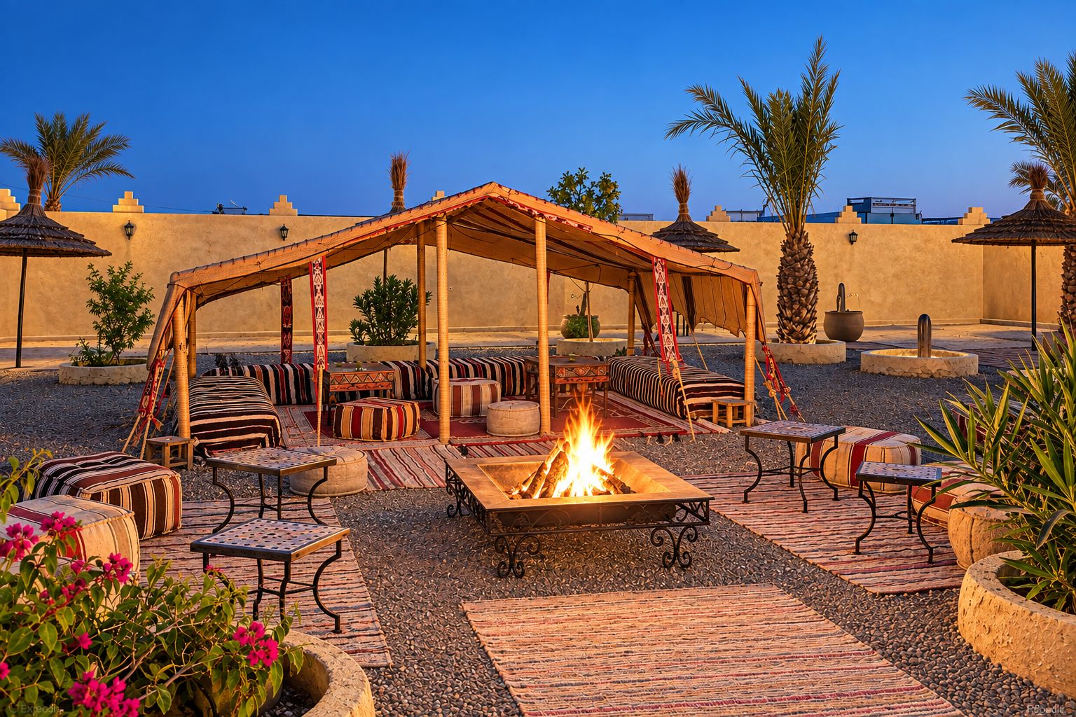 An outdoor seating area with a fire pit, cushioned seating, and a covered structure.