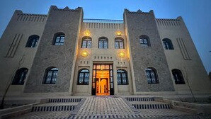A large, historic building with a central entrance, symmetrical design, and a tiled ground floor. - Riad La Luna (Merzouga)