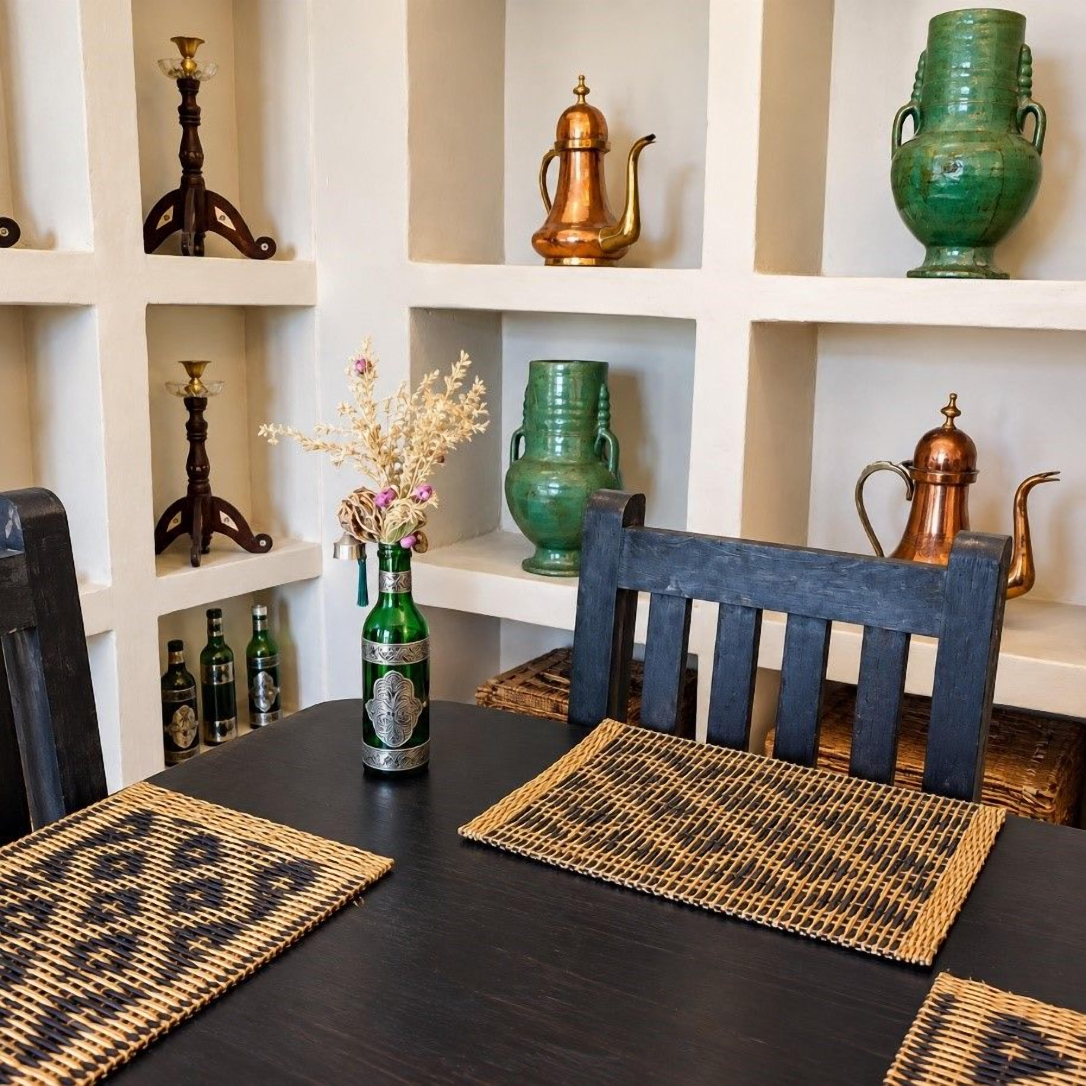 A dining area with a dark wooden table, woven placemats, and a chair with a blue cushion.