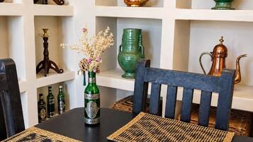 Un coin repas avec une table en bois foncé, des sets de table en fibres tressées et une chaise dotée d’un coussin bleu.