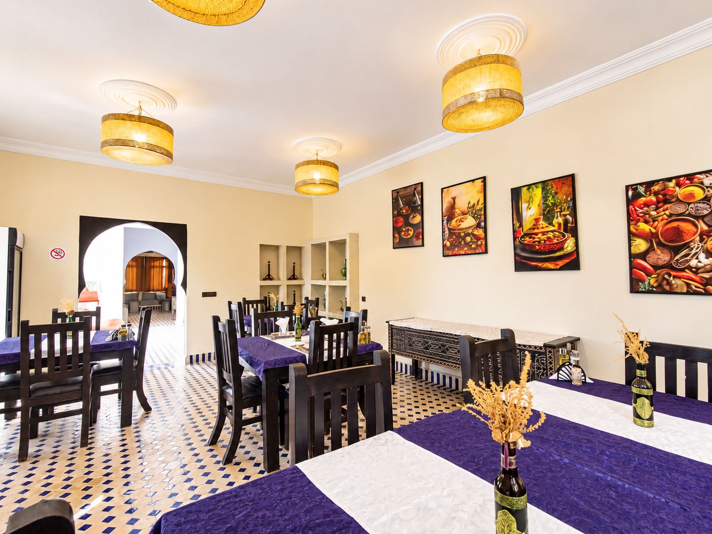 Un comedor con mesas, sillas y lámparas colgantes.