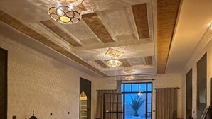 A spacious living area with a patterned floor, a sofa, chairs, and a table. - Riad La Luna (Merzouga)