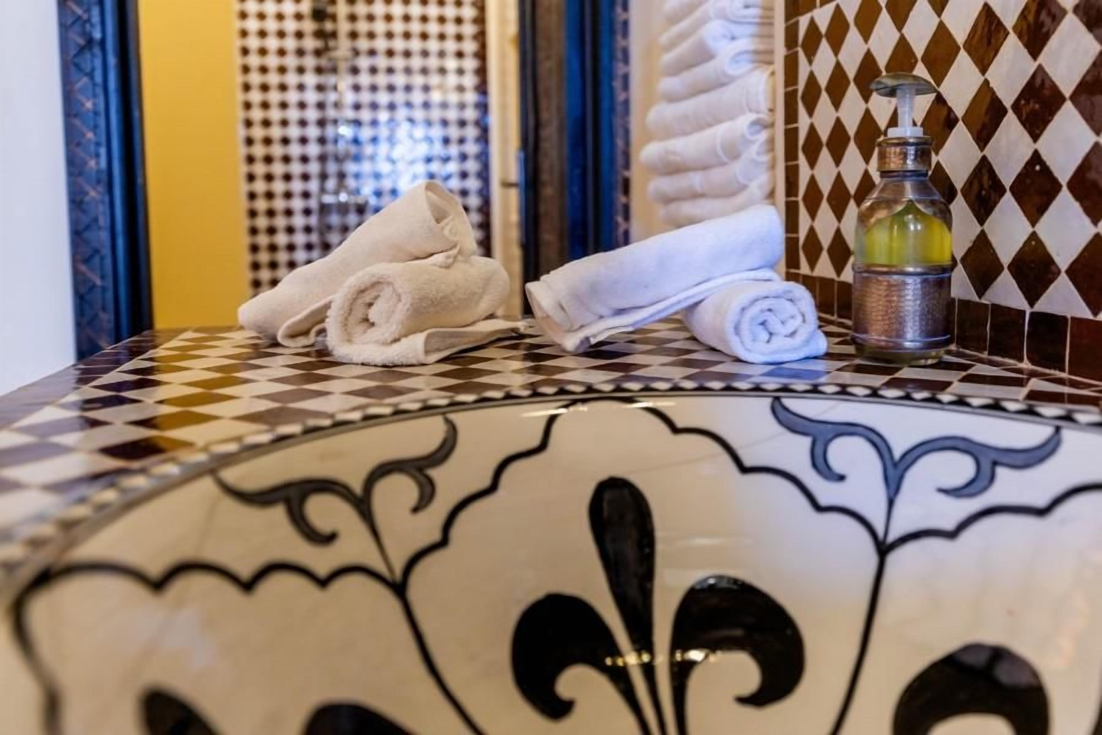 A bathroom with a checkered floor, a decorative tile wall, and a bottle of soap.