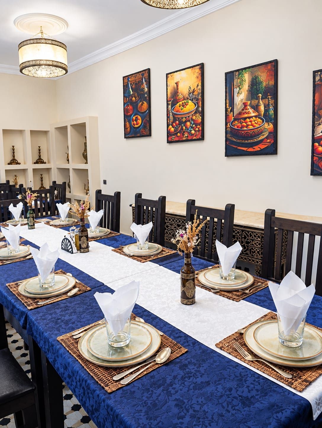 A long dining table set with blue tablecloths, white napkins, and gold-rimmed plates.