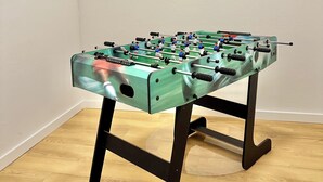 Ett fotbollsspelbord i ett rum med trägolv och vita väggar.