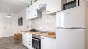 A modern kitchen with white cabinetry, a built-in oven, a microwave, and a wooden countertop.
