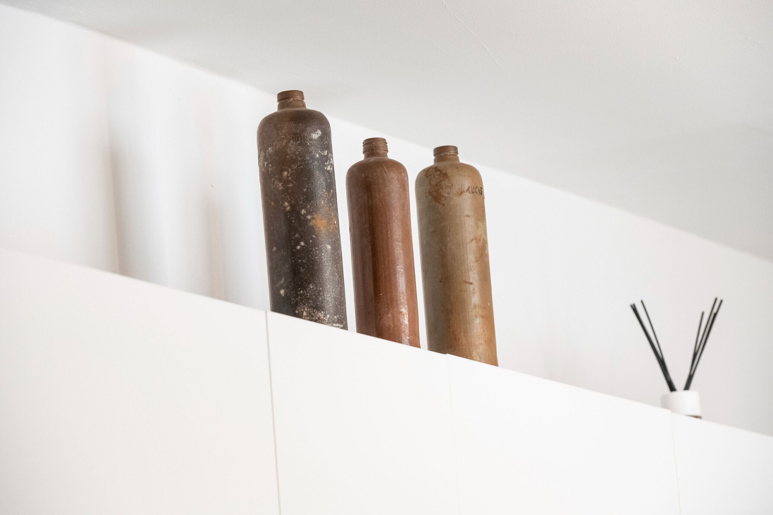 Drie cilindervormige objecten in verschillende kleuren en texturen op een witte ondergrond.