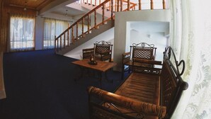 A spacious room with a wooden staircase, a sofa, and a table. - The Nun Kun Residency Kargil (Kargil)