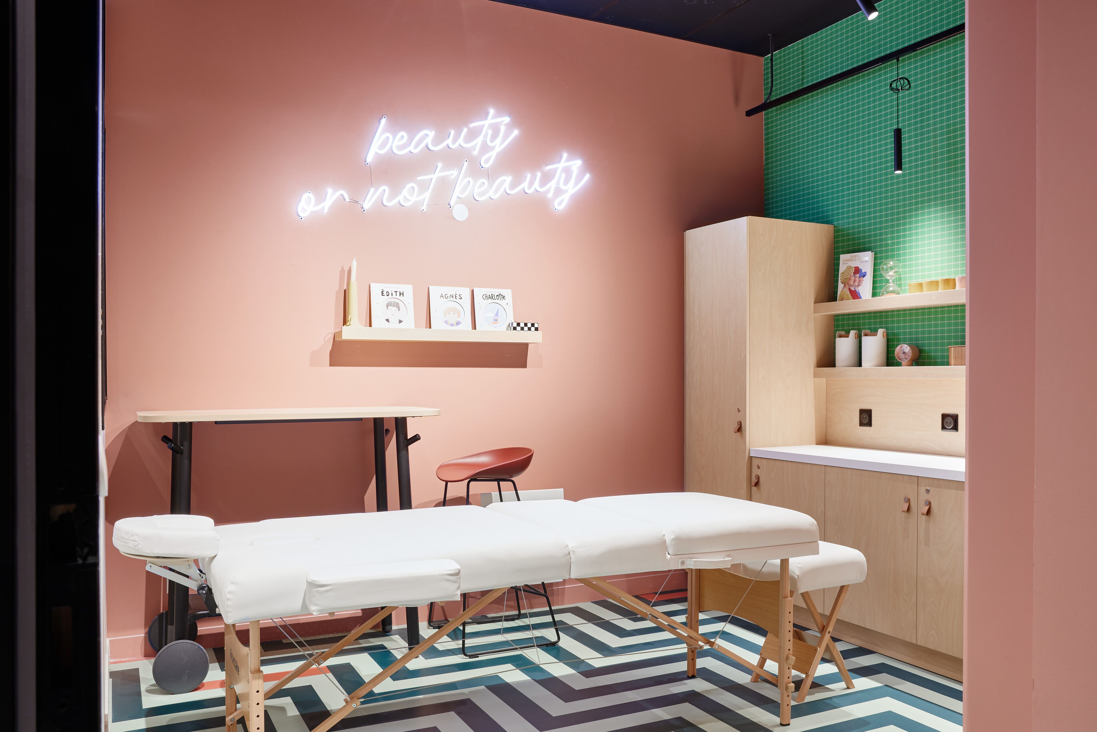 A modern room with a massage table, a neon sign, and a green tiled wall.