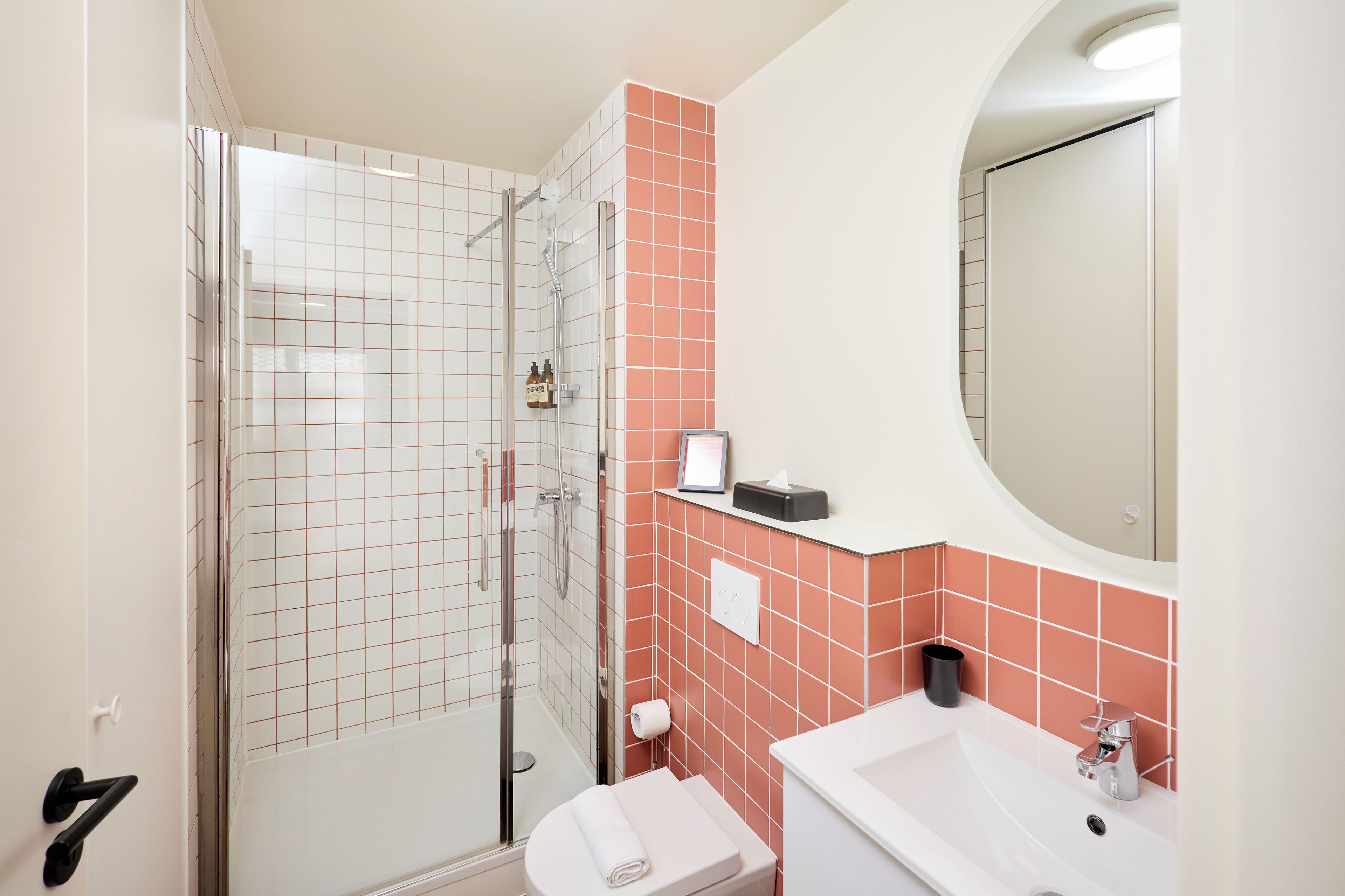 Un bagno con doccia vetro-muraria, un water, un lavandino e uno specchio.
