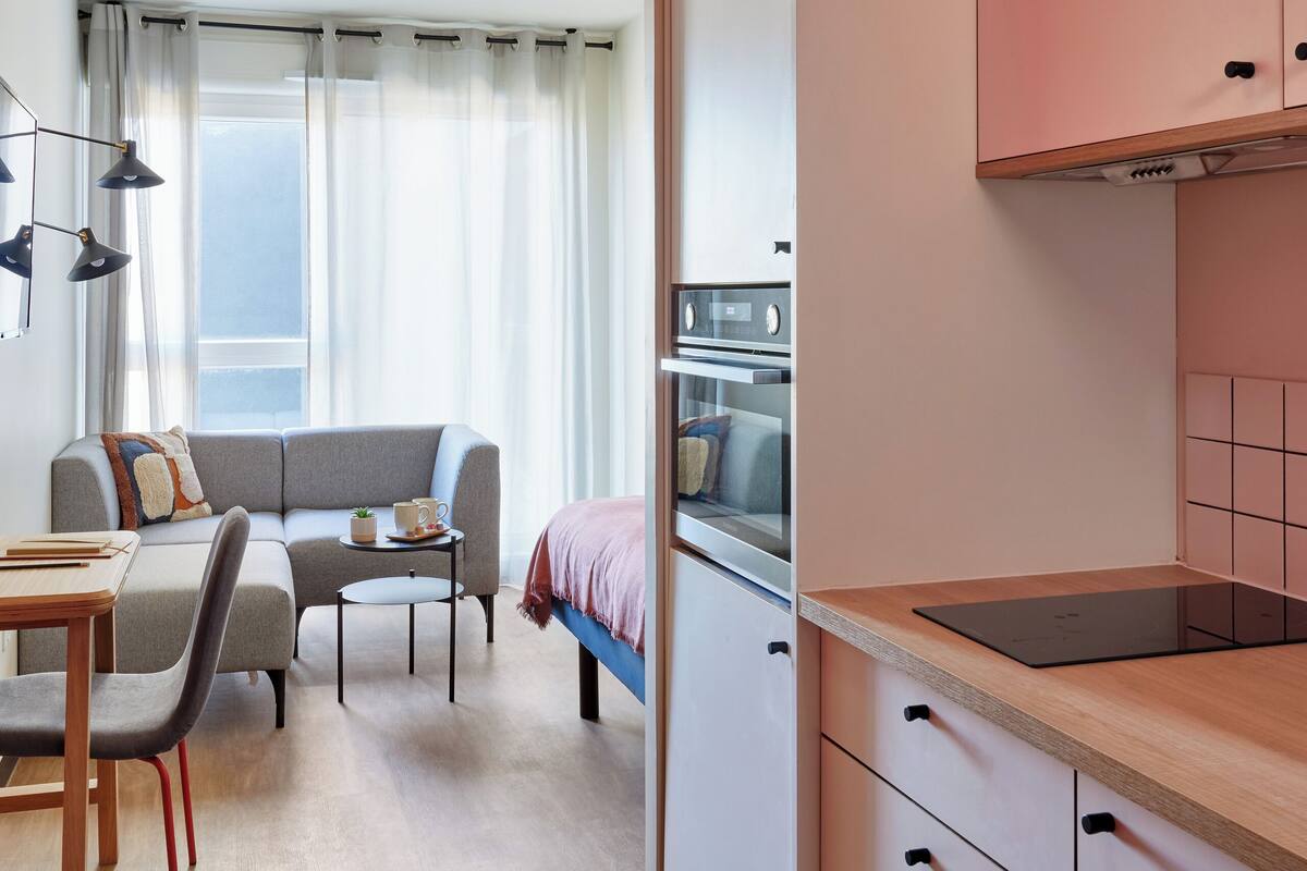 Een compacte hotelkamer met een kitchenette, een eethoek en een bank.