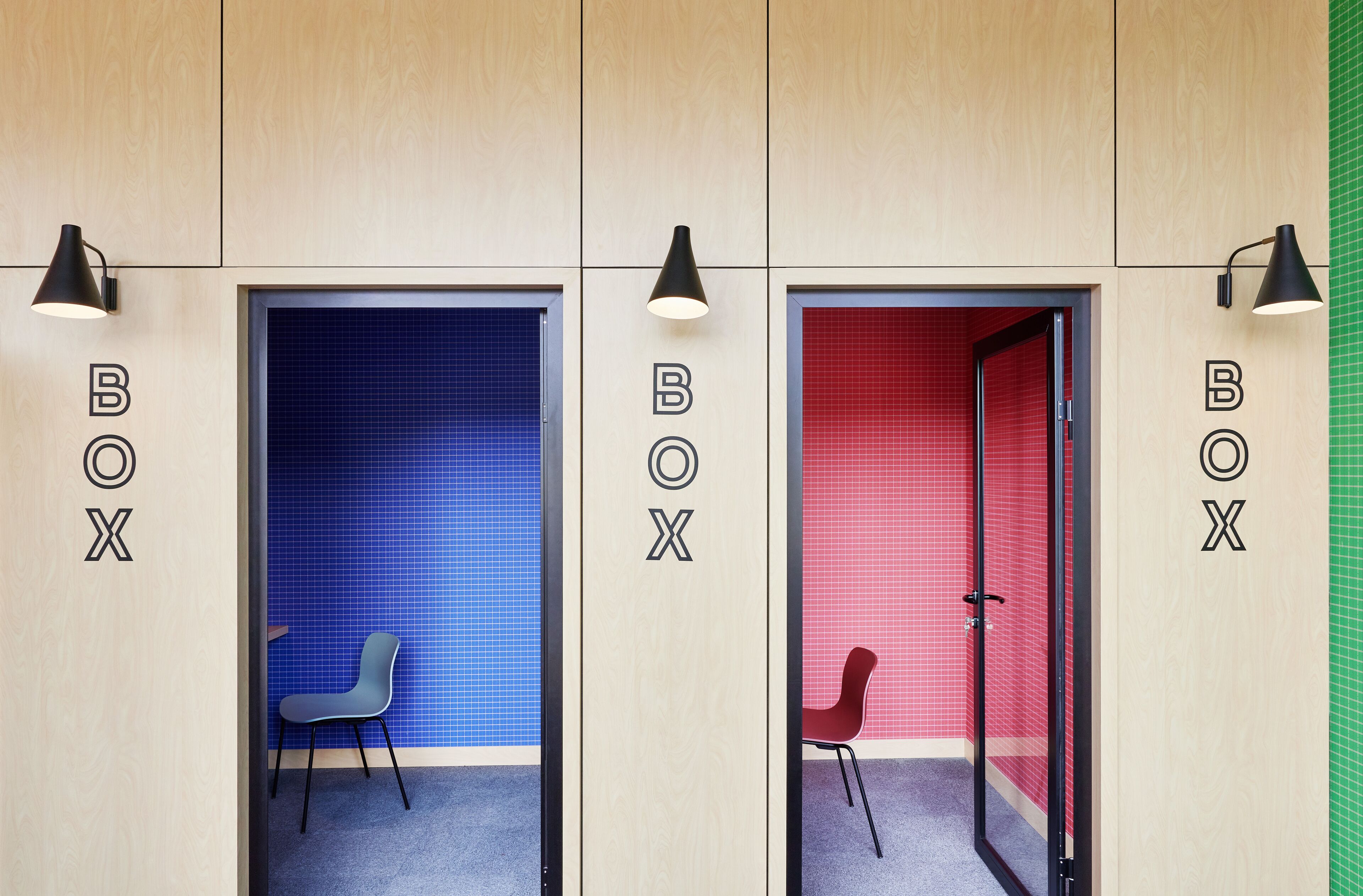 Drie kamers met de aanduiding 'BOX', elk met muren in verschillende kleuren (blauw, rood en groen), een stoel en een lamp.