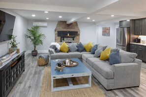 A modern living room with a grey sofa, a coffee table, and a fireplace. - Lower Level Apartment Close to Town and Beaches (2314) (Brewster)