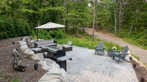 An outdoor patio with a brick floor, a built-in grill, and seating including a sofa and chairs.