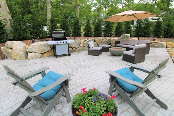 An outdoor patio with a grill, seating area, and potted plants. - Lower Level Apartment Close to Town and Beaches (2314) (Brewster)