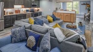 A modern kitchen with dark cabinets, a central island, and a dining area with a chair and table.