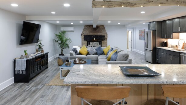 A modern kitchen with dark cabinets, a large island, and a built-in oven.