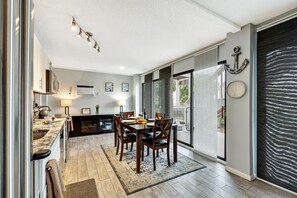 A modern kitchen with a dining area, a large window, and a view of the outdoors.