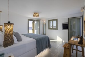 A bedroom with a bed, bedside table, and a view of the sea.