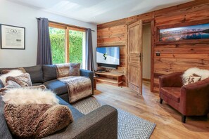 A living room with a sofa, a television, and a wooden wall.