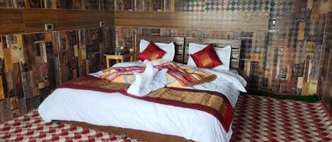 A bed with a checkered red and white floor, a wooden headboard, and a patterned bedspread.
