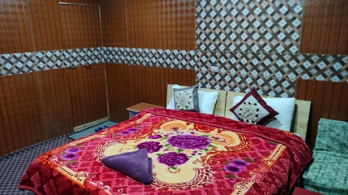 A bedroom with a wooden headboard, a patterned curtain, and a floral bedspread.