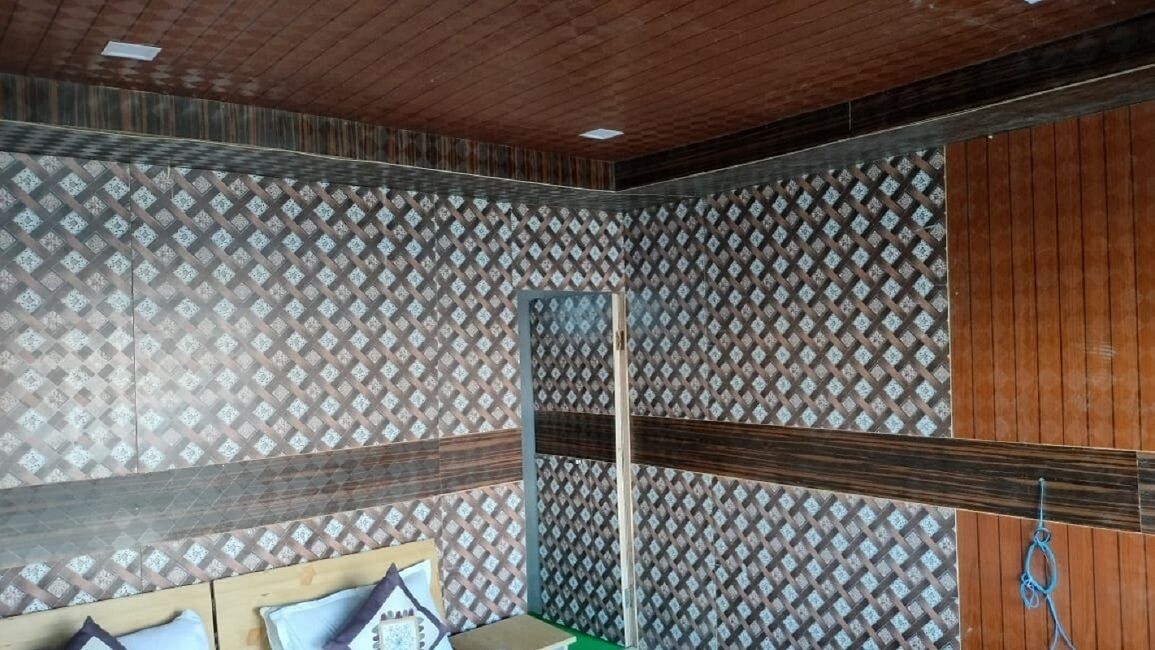 Una habitación con papel tapiz estampado, paneles de madera y un espejo.