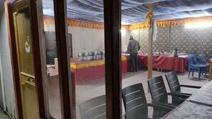 Une pièce avec une table mise pour un repas, une personne debout près d’une table de buffet et un mur décoré de motifs.