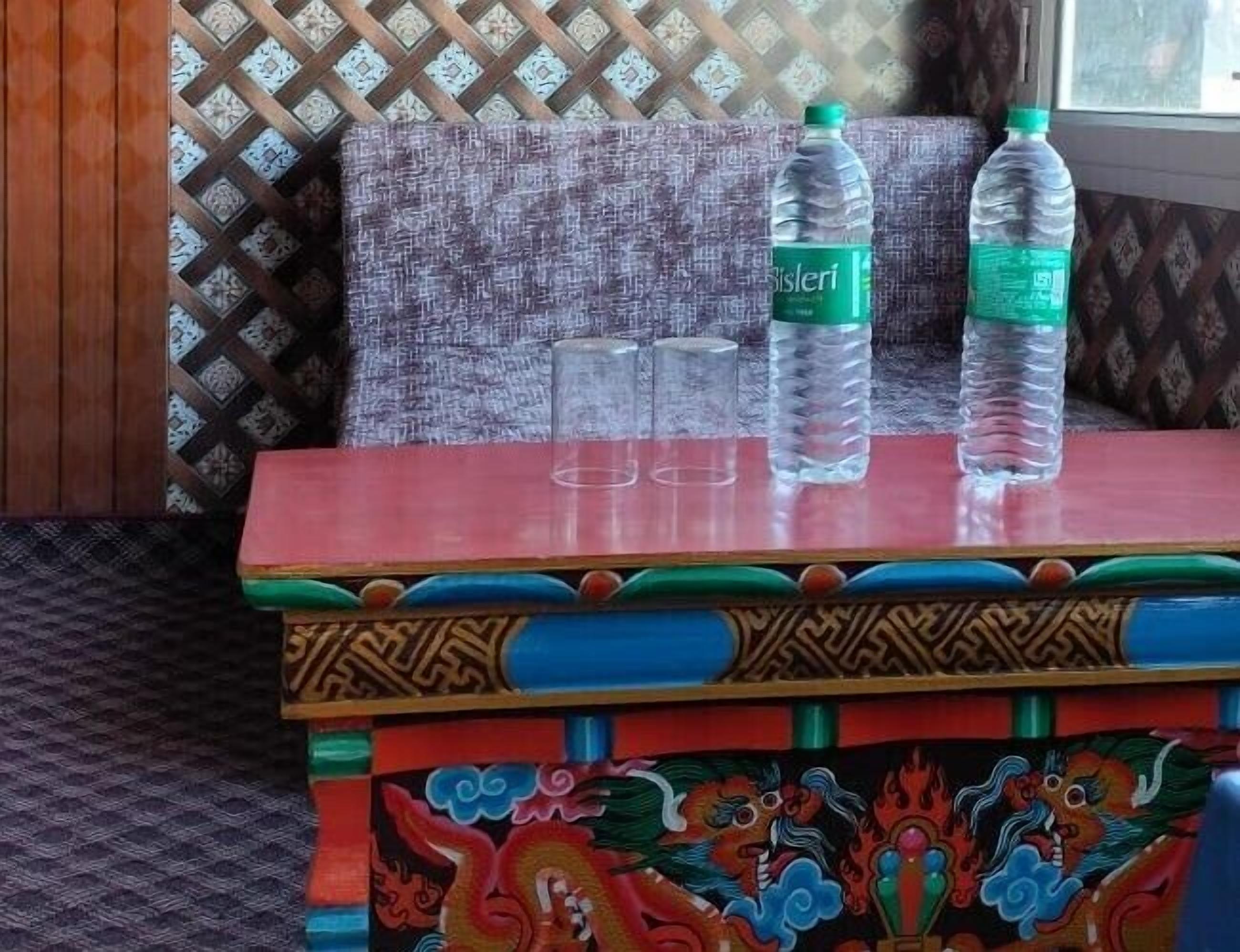A colorful table with two water bottles and two empty glasses.