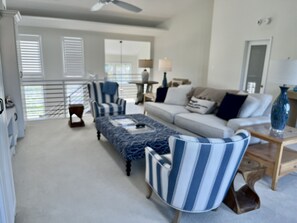 Relax in a spacious living area with a comfortable sofa set, ottoman, and armchairs.