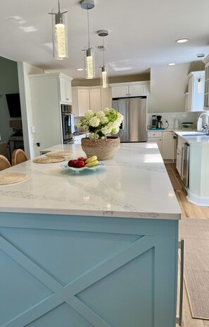 Enjoy cooking in this well-equipped kitchen with a central island, stainless steel appliances, and pendant lights.