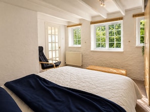 A bedroom with a bed, a chair, a window, and a radiator.