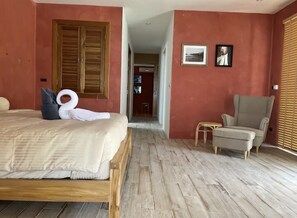 A bedroom with a bed, a chair, and a wooden floor.