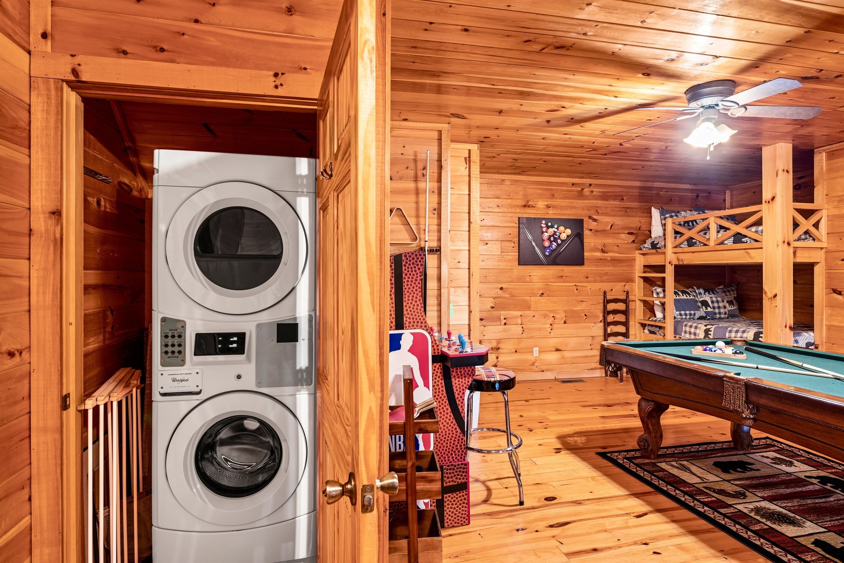 A laundry room with stacked washers and dryers, a pool table, and a ceiling fan.