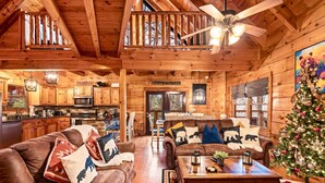 A cozy cabin interior with a wooden interior, a dining area, a living room with a fireplace, and a decorated Christmas tree. - 3 Primary Suites, Amazing location, Hot Tub (Pigeon Forge)