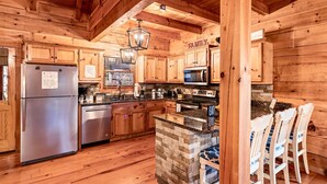 A wooden cabin-style kitchen with a stone island, stainless steel appliances, and a 'FAMILY' sign. - 3 Primary Suites, Amazing location, Hot Tub (Pigeon Forge)