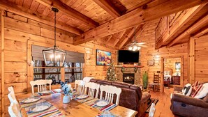 A wooden cabin interior with a dining area, fireplace, and cozy seating. - 3 Primary Suites, Amazing location, Hot Tub (Pigeon Forge)
