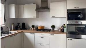 Una cocina moderna con armarios blancos, estufa a gas, microondas y horno.
