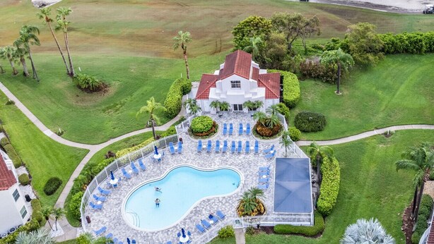 An aerial view of a resort with a swimming pool surrounded by lounge chairs and palm trees.