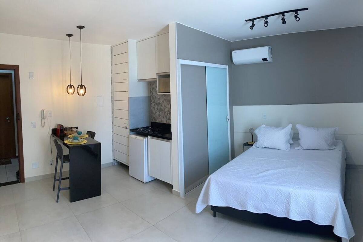 A compact hotel room with a bed, kitchenette, and a small dining area.