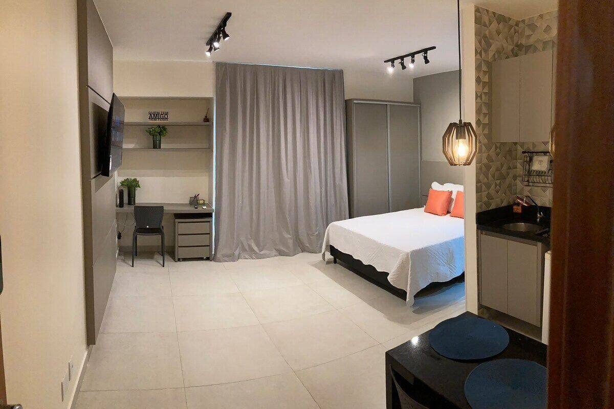A compact bedroom with a bed, a desk, and a kitchenette.