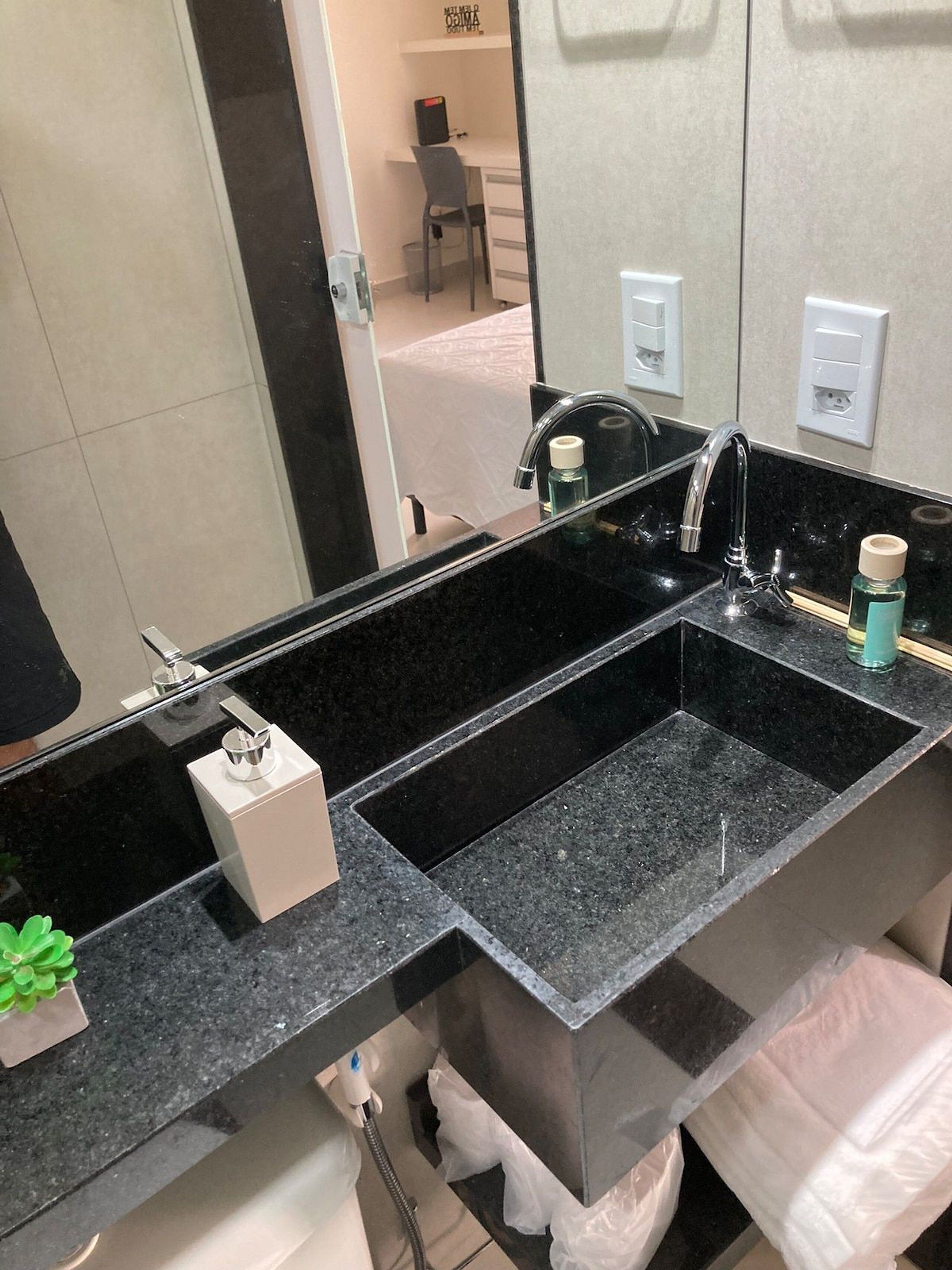 A modern bathroom with a black granite sink, a mirror, and a towel rack.