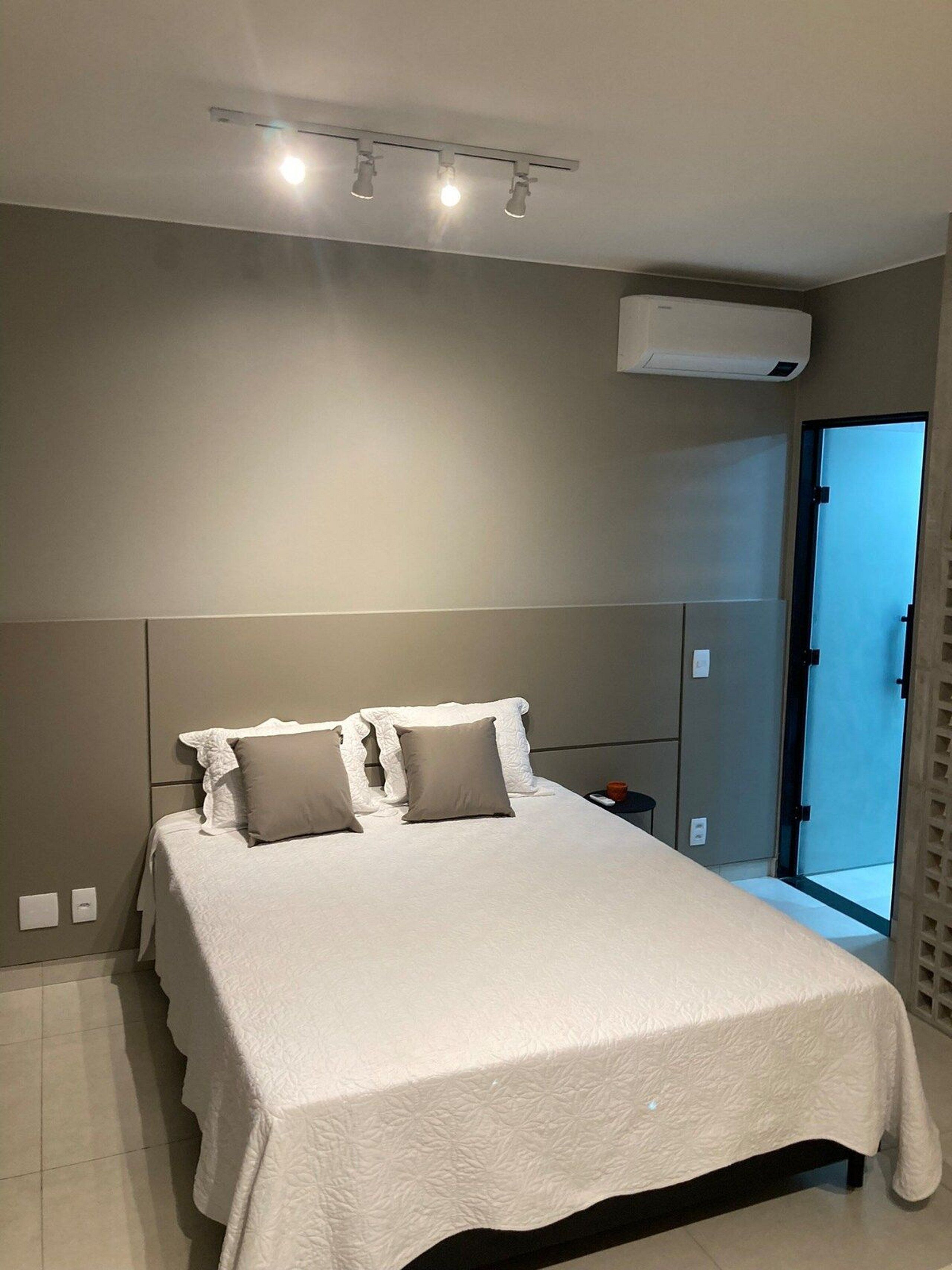 Een moderne slaapkamer met een groot bed, een nachtkastje en een airconditioning.
