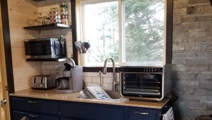 Une cuisine avec des meubles de couleur bleu foncé, un four à micro-ondes, un grille-pain et une cuisinière.
