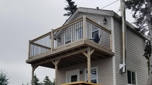 Une maison à deux étages dotée d’une terrasse en bois et d’un escalier menant à l’étage supérieur.