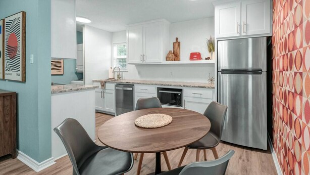 A modern kitchen with white cabinets, stainless steel appliances, and a round wooden table with chairs. - Bauhaus-1st Floor, King Beds, Walk to A&M Campus (Bryan)