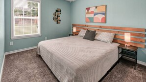A bedroom with a bed, two bedside tables, a ceiling fan, a window with blinds, and a wall art piece. - Bauhaus-1st Floor, King Beds, Walk to A&M Campus (Bryan)