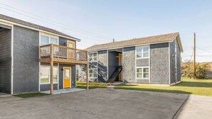 A two-story building with a balcony on the first floor and a staircase leading to the second floor. - BethyKay: 2 Bedroom, Walk to A&M, Comfy King Beds (Bryan)