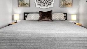 A neatly made bed with a patterned bedspread, two bedside lamps, and three framed artworks on the wall. - Big Easy: 2 Bedrooms, 2nd floor, Walk to A&M, Comfy King Beds (Bryan)
