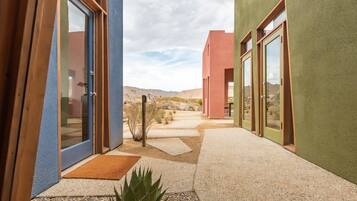 A modern building with large glass doors, a pathway, and a desert landscape in the background.